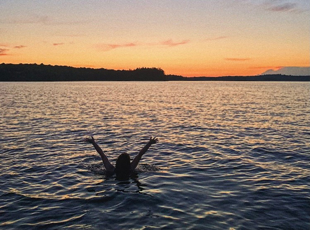 Silhouette of person swimming in Lake Muskoka during sunset