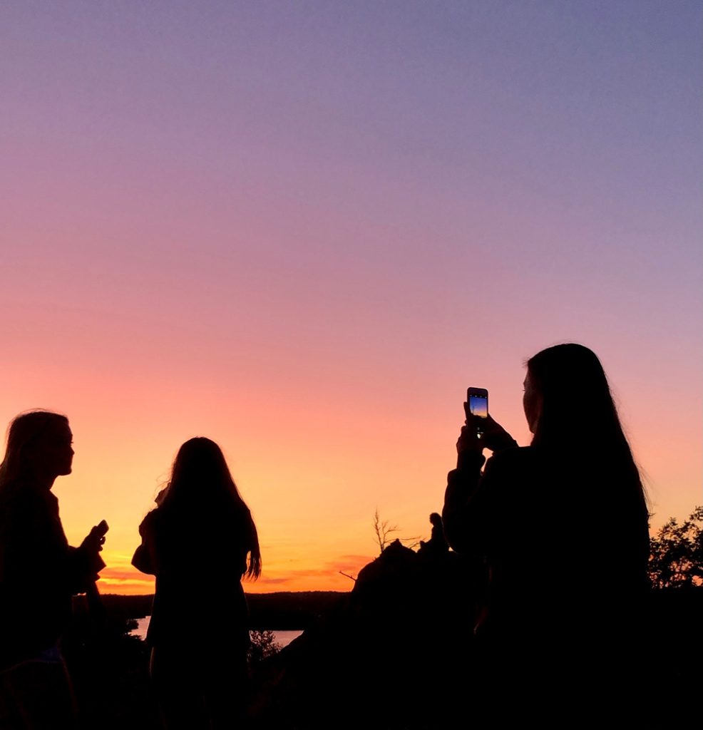 Silhouette of a group of people taking photos during sunset